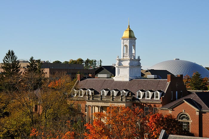 University of Connecticut campus in autumn, with a white cupola and gold dome rising above brick buildings and fall foliage